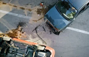 Accidente de tráfico con varios vehículos implicados vistos desde arriba, uno volcado y otro con daños frontales, ilustrando siniestros complejos que requieren asesoramiento legal especializado